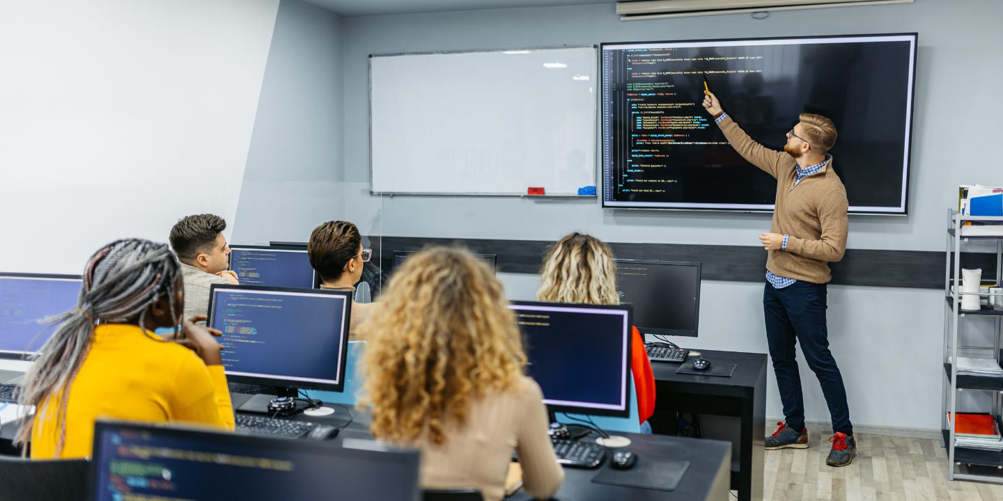 teacher helping in a coding bootcamp program for teens